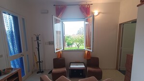 A living room with two brown armchairs, a small table, and a window with curtains. - Villa Specchiarica (San Pietro In Bevagna)