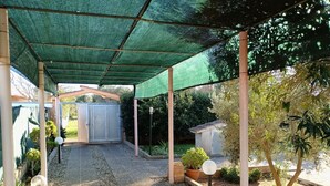 A covered patio area with a gravel path, surrounded by plants and trees. - Villa Specchiarica (San Pietro In Bevagna)