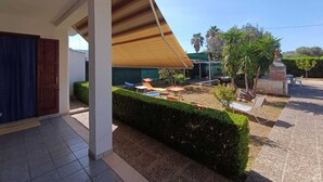 A covered outdoor area with a wooden roof, a hedge, and a small garden with a bench and a statue. - Villa Specchiarica (San Pietro In Bevagna)