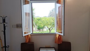 A room with an open window, two chairs, a small table with a menu, and a cricket bat leaning against the wall. - Villa Specchiarica (San Pietro In Bevagna)