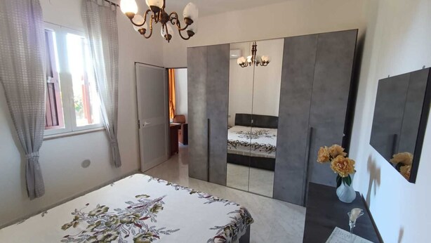 A bedroom with a bed, a dresser, a mirror, and a chandelier. - Villa Specchiarica (San Pietro In Bevagna)