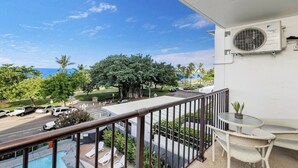 A balcony with a view of the ocean, a pool, and a white air conditioning unit. - Studio 211-seaside Serenity: Your Perfect Retreat (North Ward)