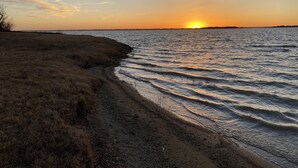 Ein Sonnenuntergang über ruhigem Wasser mit einer grasbewachsenen Uferlinie.