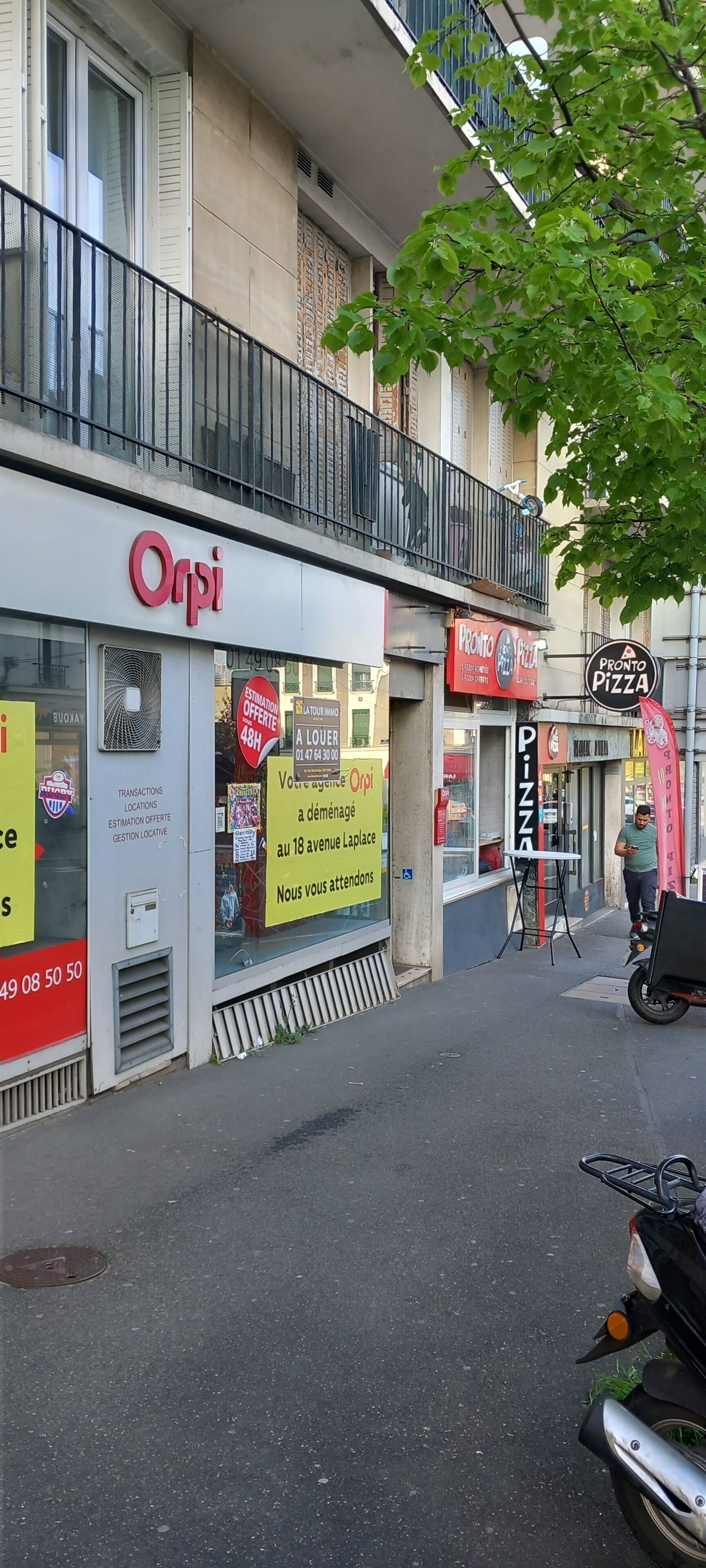 A storefront with a sign for 'Orpi' and another for 'Pronto Pizza'.