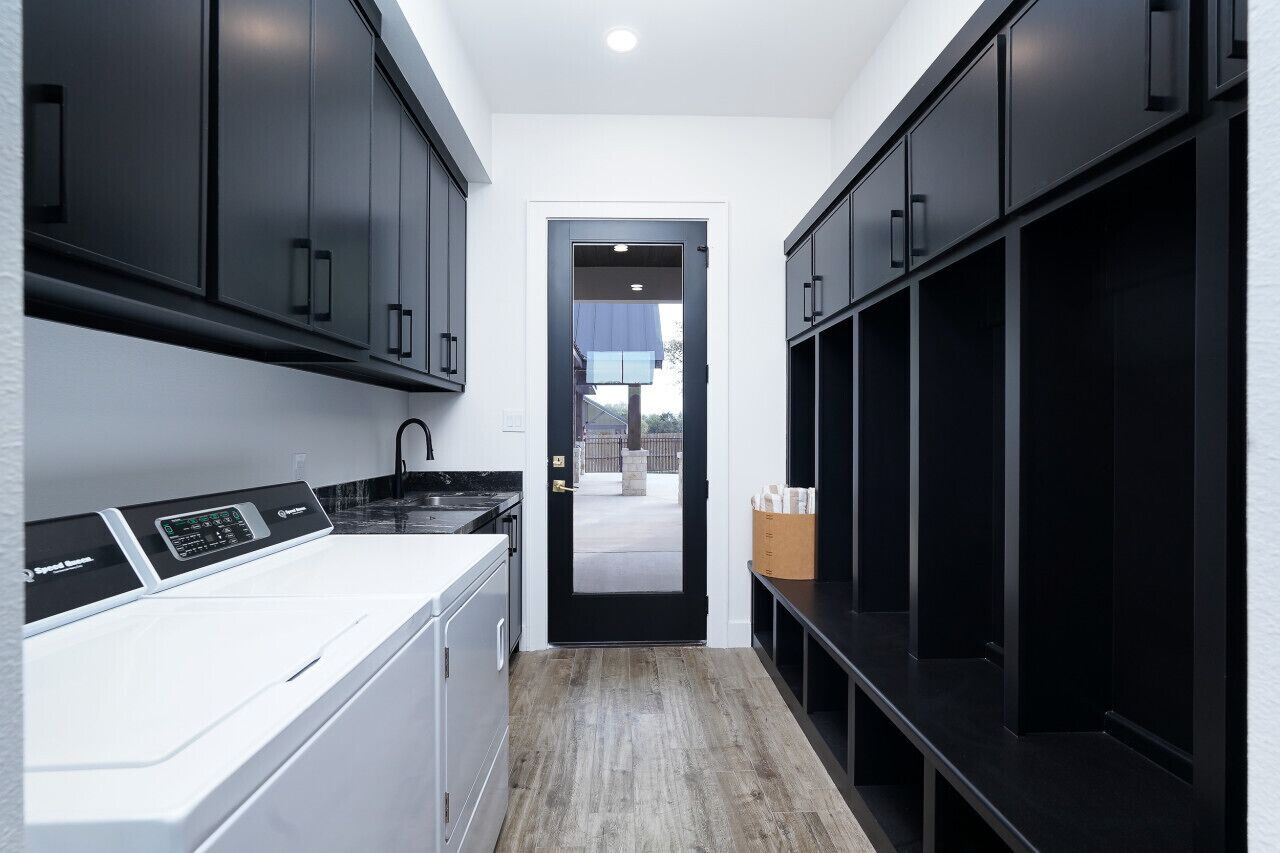 Une cuisine moderne avec des meubles de couleur sombre, un plan de travail blanc et un lave-linge encastré.
