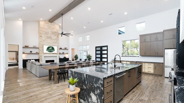A spacious kitchen with a large island, wooden cabinets, and a stone accent wall. - Near Frio~Pool~Hot tub~Two Kitchens~For 30 (Concan)