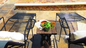 A pool area with a stone wall, outdoor seating, and a barbecue. - Casa Magu Merida (Mérida)