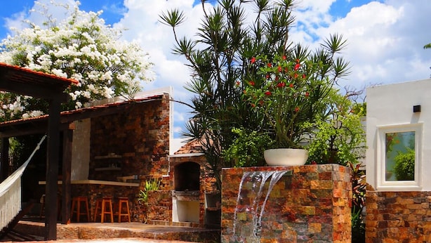A swimming pool with a waterfall feature, surrounded by stone walls and a wooden pergola. - Casa Magu Merida (Mérida)