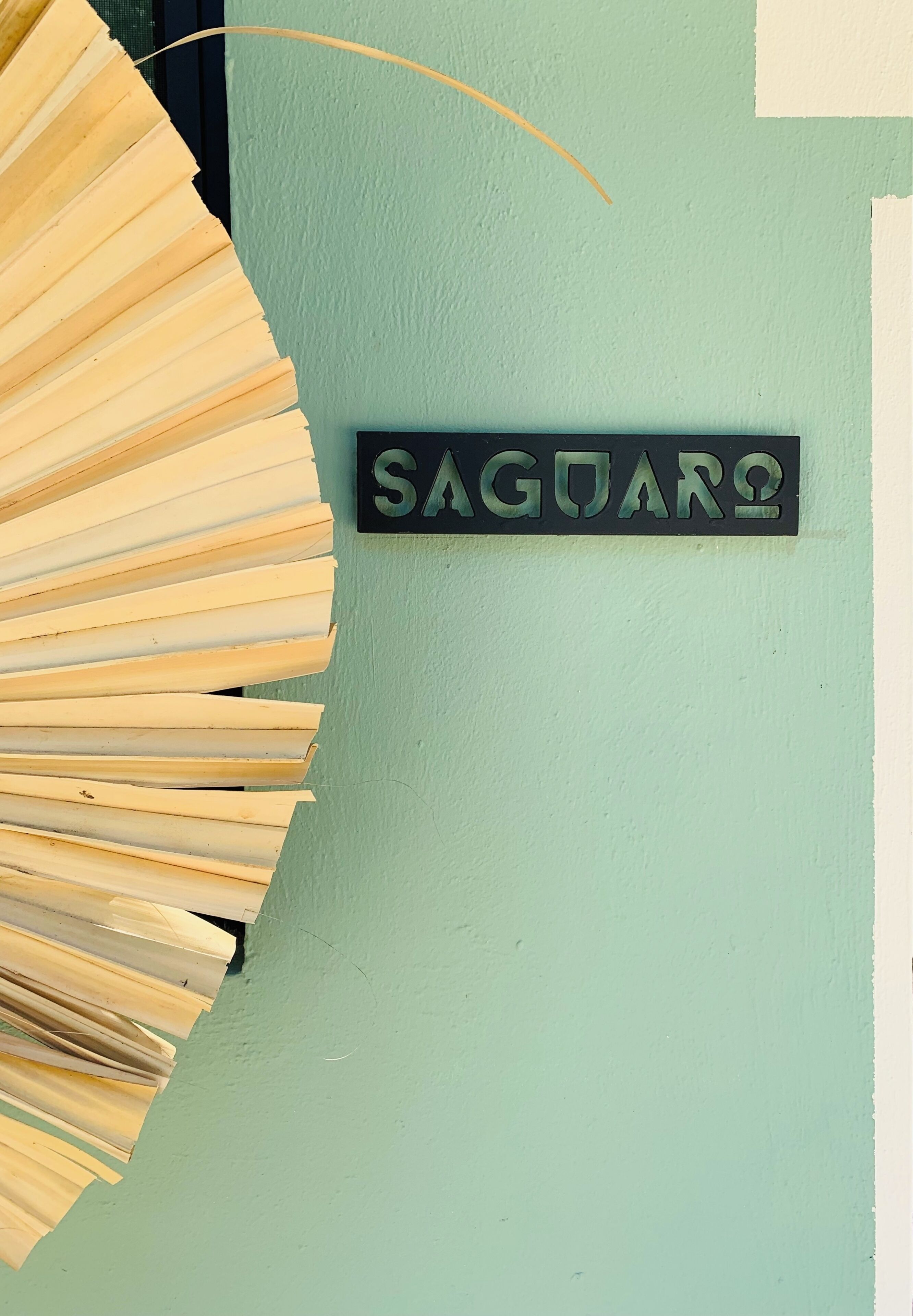 A wall with a sign that reads 'SAGUAR' and a decorative sun-like structure.