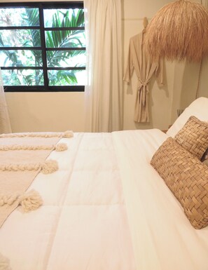A bed with a woven pillow, a white throw, and a window with curtains. - Casa Magu Merida (Mérida)