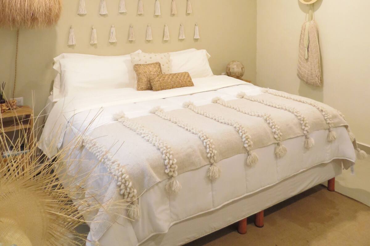 A bedroom with a bed, a hanging light fixture, and wall-mounted tassels.
