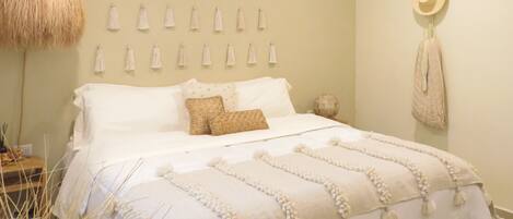 A bedroom with a bed, a hanging light fixture, and wall-mounted tassels.