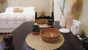 A bedroom with a bed, bedside table with decorative bowls, a wall-mounted clock, and a potted plant. - Casa Magu Merida (Mérida)