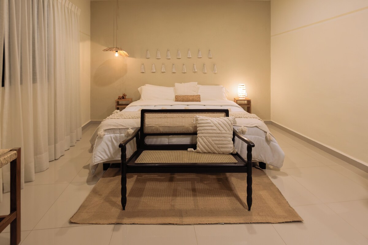 Ein Schlafzimmer mit einem Bett, Nachttischen, einem Sessel und einem Teppich.