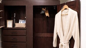 A walk-in closet with a robe hanging, a wooden wardrobe, and a small shelf with items. - Casa Magu Merida (Mérida)