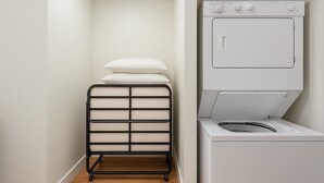 A laundry room with a white washing machine and a black drying rack with folded towels. - Jazzy Downtown Studio w/ Piano! (Dallas)