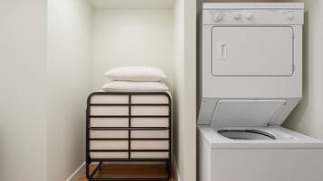 A laundry room with a white washing machine and a black drying rack with folded towels.