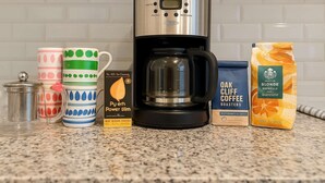 A kitchen counter with a coffee maker, a mug, a coffee pod, and a bag of coffee. - Jazzy Downtown Studio w/ Piano! (Dallas)