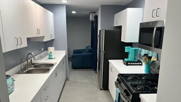 Una cocina moderna con armarios blancos, una estufa, un fregadero y un refrigerador.
