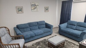 Una sala de estar con dos sofás azules, una silla de madera y un tapete gris.