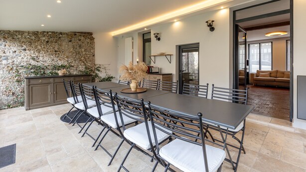 A spacious dining area with a long table and chairs, a stone wall, and a kitchen area visible through an open doorway. - "Cap sur Honfleur", House in the center of Honfleur 12P (Honfleur)