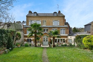 A two-story brick house with a central entrance, a small porch, and a garden with palm trees and a pathway leading to the door. - Villa Jane'Laur, Magnificent mansion with garden 11 P (Honfleur)