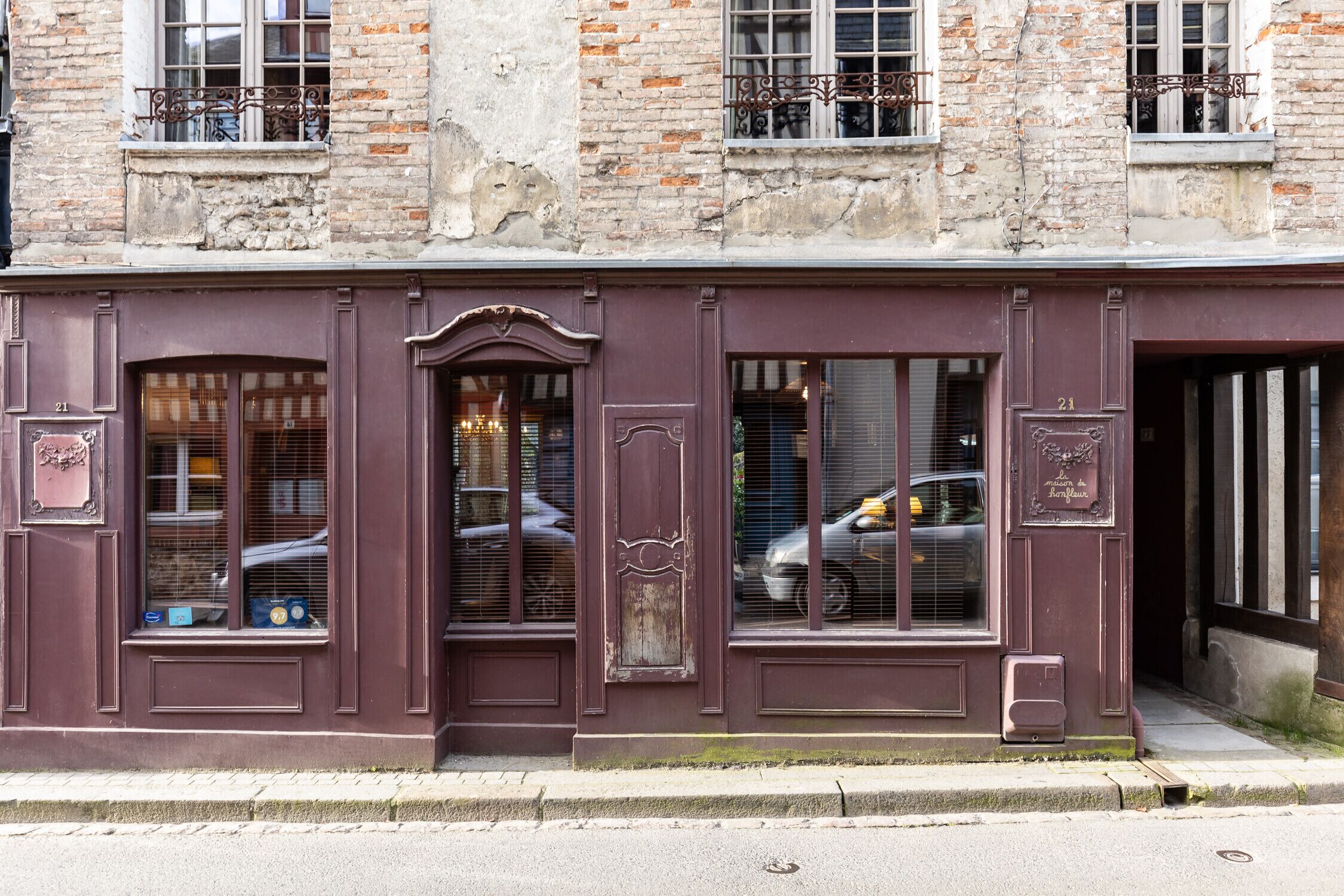 Un bâtiment à la façade sombre, doté de grandes fenêtres et d’une porte bien visible.