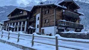 Un chalet en bois doté de balcons, situé au pied d’une montagne enneigée.