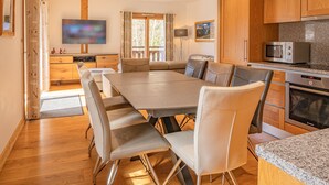 Une cuisine moderne avec un coin repas, des meubles en bois, un four à micro-ondes et un four Bosch.
