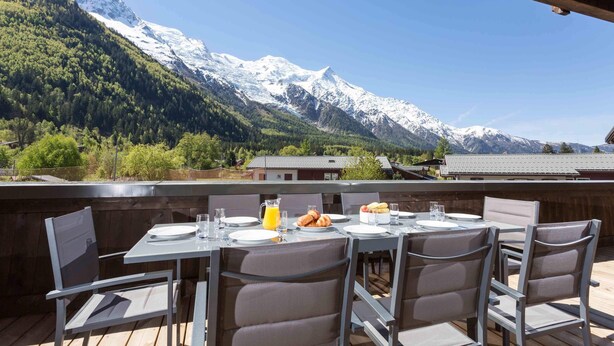 Un espace de restauration en plein air avec des tables et des chaises, une carafe de jus d’orange et un verre d’eau.