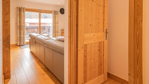 Une pièce avec une porte en bois, un canapé, une fenêtre avec des rideaux et une vue sur l’extérieur.