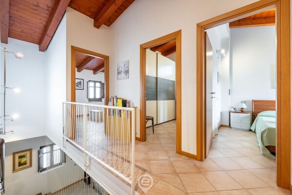 A spacious room with a balcony, a bed with a green bedspread, and a wooden ceiling.