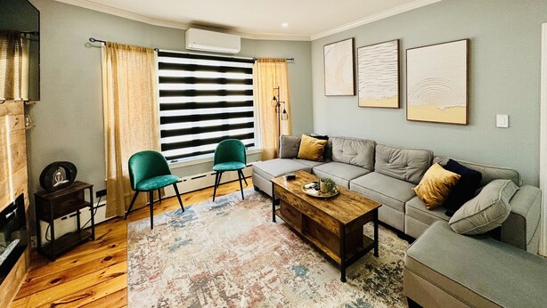 Un salon comprenant un canapé, deux fauteuils, une table basse et un tapis à motifs.