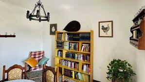 A room with a dining table, chairs, a chandelier, a bookshelf, and a potted plant. - Il Podere di Casa Rossa Pienza (Pienza)