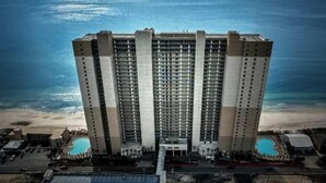 Un hôtel de grande hauteur, avec de nombreux étages, une piscine et une vue sur la plage.