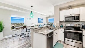Une cuisine moderne avec des armoires blanches, des appareils en acier inoxydable et une vue sur la ville.