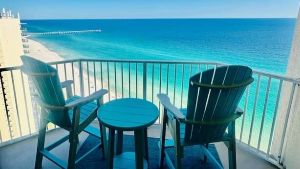 Un balcon avec vue sur l’océan, deux chaises et une petite table.