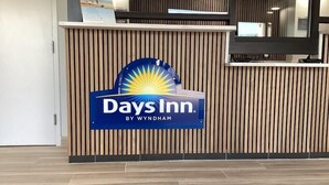 A reception desk with a Days Inn logo, wooden paneling, and a tiled floor.