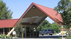 A building with a red roof, a covered entrance, and a sign indicating 'CENTER LANE - 12 FT.' - Travelodge by Wyndham Red Bluff South of Redding (Red Bluff)