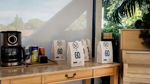 A kitchen counter with a coffee maker, sugar, creamer, and paper bags labeled 'GO.' - Travelodge by Wyndham Red Bluff South of Redding (Red Bluff)