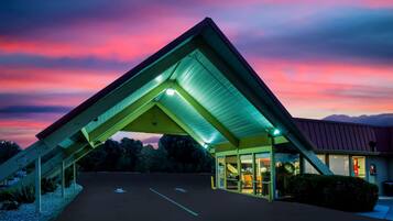 A building with a distinctive triangular roof structure, a covered entrance, and a parking lot.