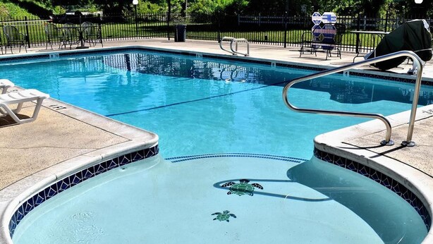 A swimming pool with a tiled edge, a hot tub, and a lifeguard chair. - Travelodge by Wyndham Red Bluff South of Redding (Red Bluff)