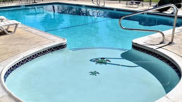 A swimming pool with a tiled edge, a hot tub, and a lifeguard chair.