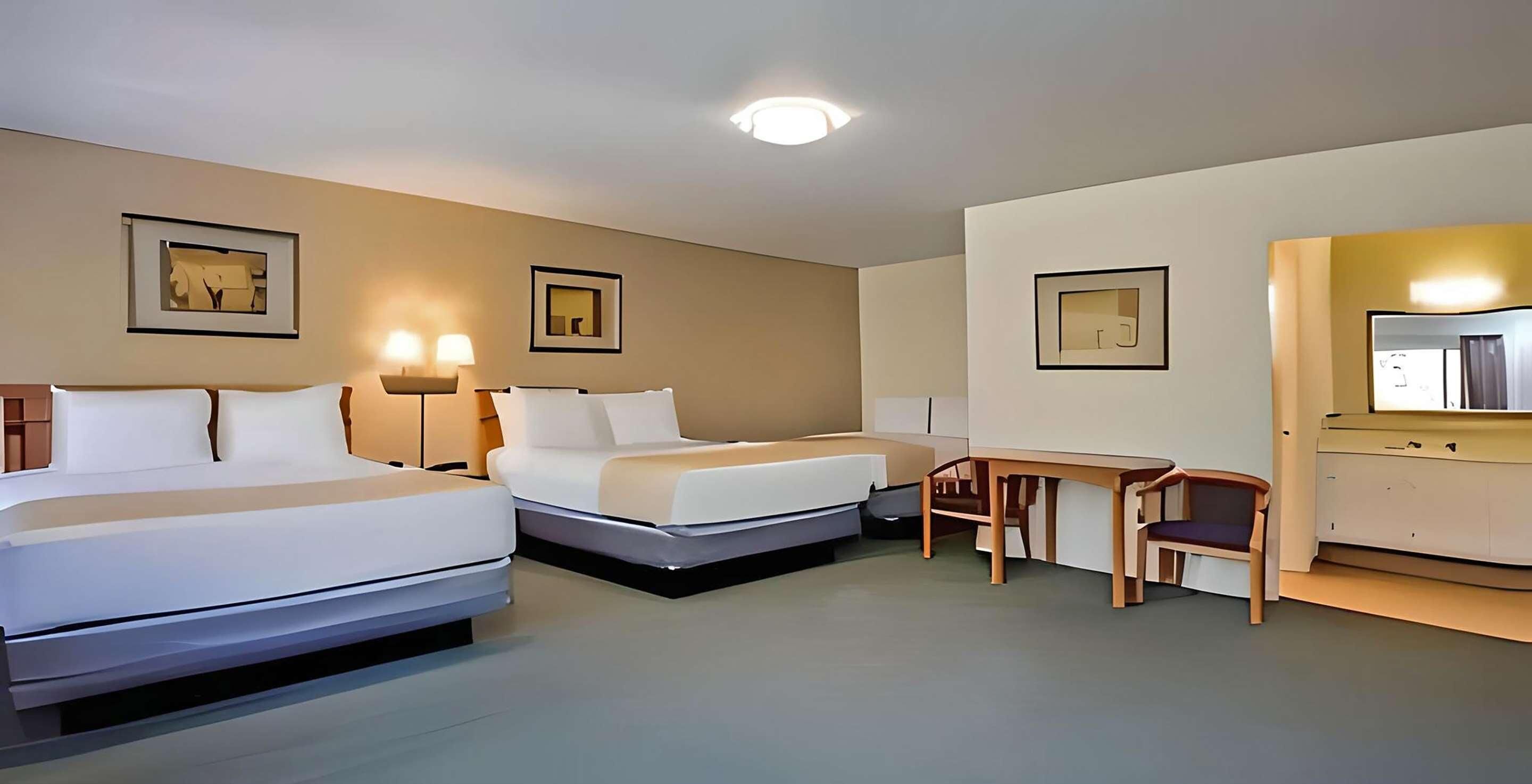 Een hotelkamer met twee bedden, een bureau, een stoel en een spiegel.