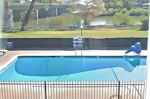 A swimming pool with a view of a park and a building in the background. - Travelodge by Wyndham Red Bluff South of Redding (Red Bluff)