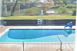 Una piscina con vistas a un parque y un edificio al fondo.