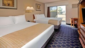 A hotel room with two beds, a TV, a desk, and a large window. - Travelodge by Wyndham Red Bluff South of Redding (Red Bluff)