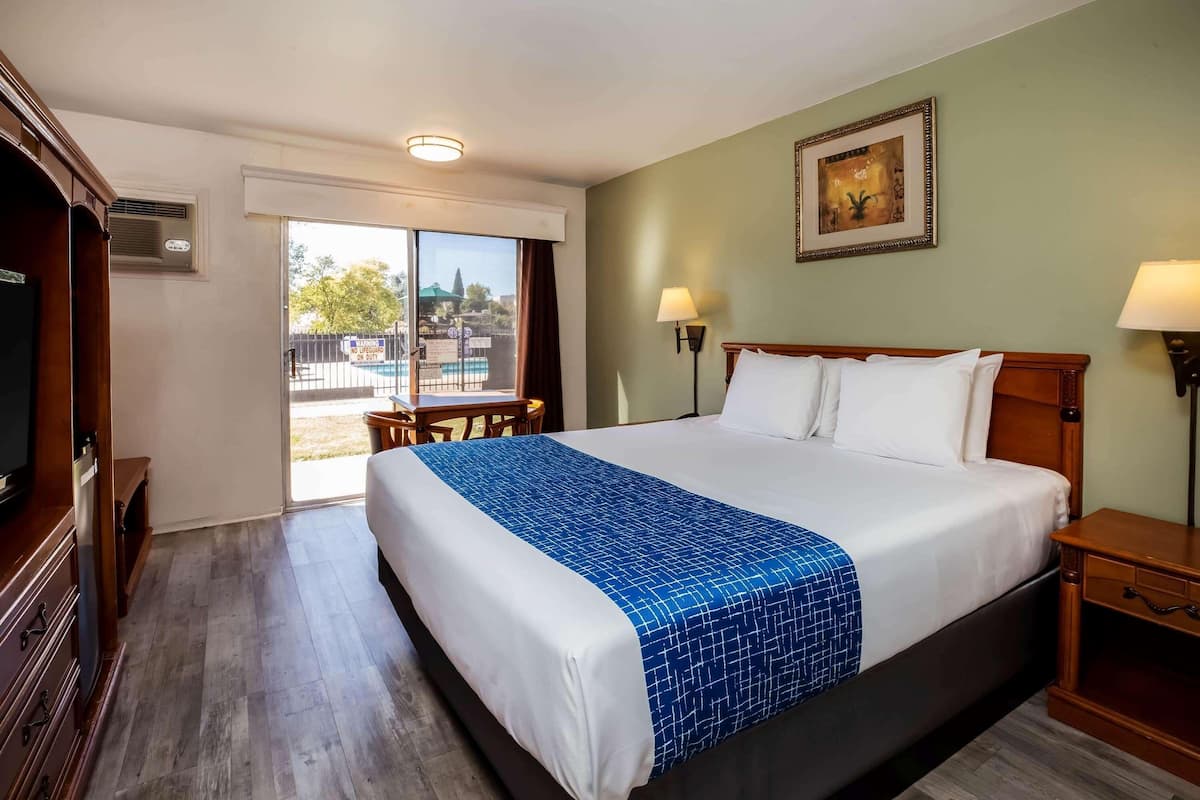 Habitación de hotel con una cama grande, televisión, escritorio y vistas al exterior.