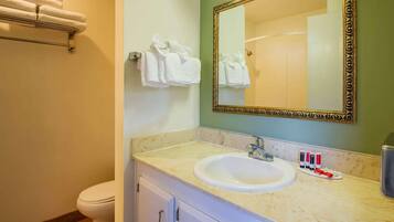 A bathroom with a sink, mirror, towel rack, and toiletries.
