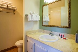 A bathroom with a sink, mirror, towel rack, and toiletries. - Travelodge by Wyndham Red Bluff South of Redding (Red Bluff)